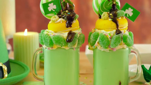 Happy St Patrick's Day on-trend holiday freak shakes milkshakes decorated with candy and lollipops.