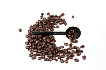 Small black plastic coffee scoop on a pile of roasted beans