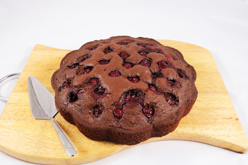 Chocolate cake with cherry on a wooden background, isolated on white. close up