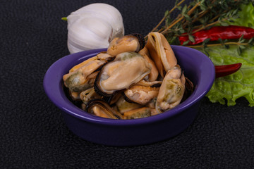 Pickled mussels in the bowl served pepper, garlic and salad