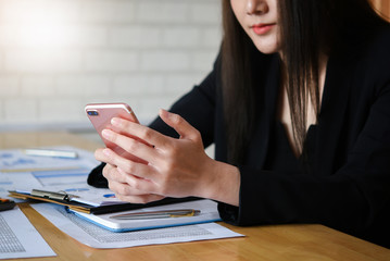 Business woman using smartphone while writing make note about cost profit at home office. Fintech concept