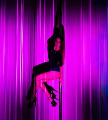 Young slim sexy woman with pink hair pole dancing in white interior. Tattoo on body.