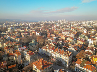 View from the height of the old town with low buildings with red tiled roofs against the blue sky and the clouds running over the horizon