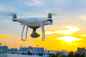 Naklejka na ściany i meble UAV drone flying over city building colorful sunset