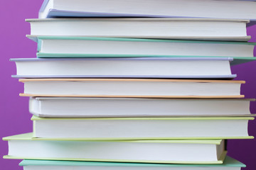 Stack of colorful books on purple background . Education background. Back to school.