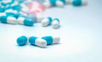 Selective focus on blue and white capsules pill spread on white background. Global healthcare. Antibiotics drug resistance. Antimicrobial capsule pills. Pharmaceutical industry. Pharmacy background.