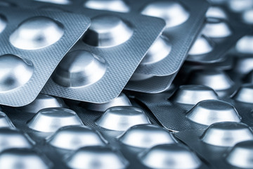 Pile of tablets pill in blister packaging to protect medicine from light. Silver aluminium foil...