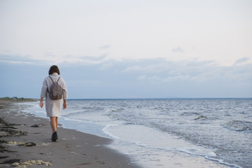 Woman in coat walking on the seashore.