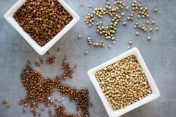 Brown and green buckwheat groats on a gray background.