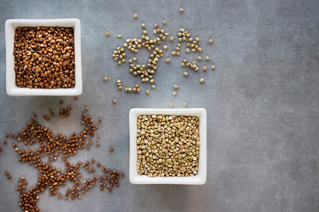 Brown and green buckwheat groats on a gray background.