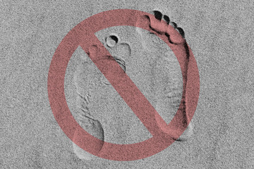 the sign is prohibited against the background of footprints in the sand pale red on gray,...