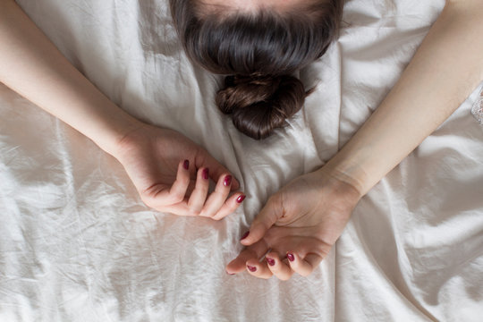 young woman lying in bed on white sheets