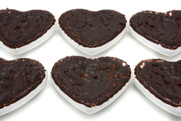 Gingerbread cookies in the form of hearts covered with white glaze and dark chocolate on an isolated background  
