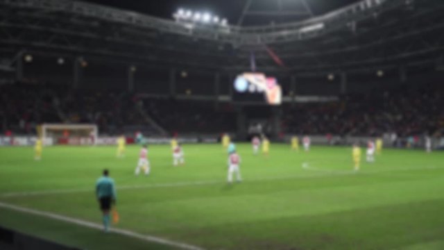 Blurred view of football game at the stadium, view from the stands, man players play football.