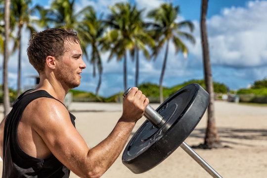 Outdoor calisthenics gym park male athlete working out on T-bar outside in summer. Man workout strength training arms biceps muscles with heavy weights. - Powered by Adobe