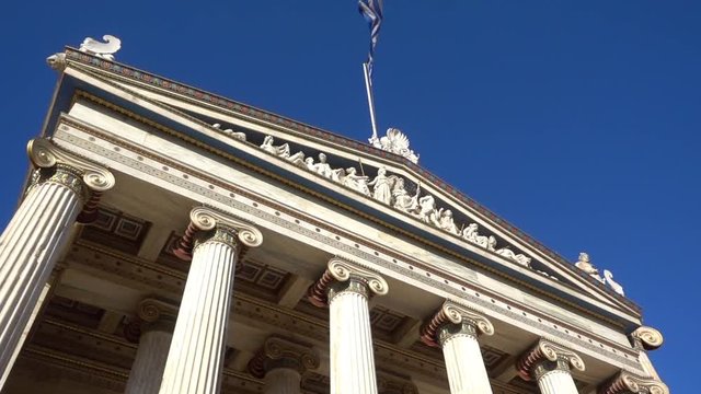 Slow Motion video from iconic neoclassic Academy of Athens facade with Greek flag waving slowly, Athens historic center, Attica, Greece        
