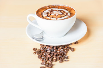 hot cappuccino with nice milk pattern with coffee bean on table