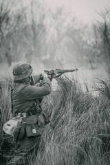 Fototapeta premium A soldier of Nazi Germany shoots a rifle for cover at enemies. Black and white photo