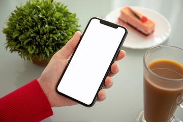  female hand holding phone with isolated screen in a cafe