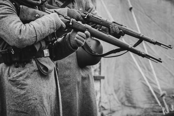 Two German soldiers of the Second World War with rifles in their hands ready to fire. Black and...