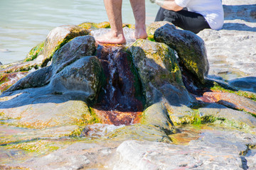 Tha man standing into the small red pools with the thermal water