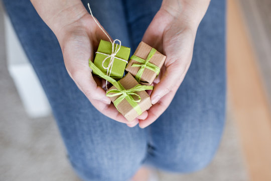 Schenken - H&auml;nde halten Geschenke in neutralen Farben verpackt in Recyclinpapier