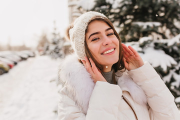 Close-up portrait of gorgeous girl with blue eyes posing on the street in snowy winter day. Outdoor...