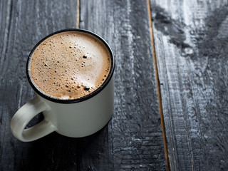 Mug of freshly brewed coffee on a dark wooden table