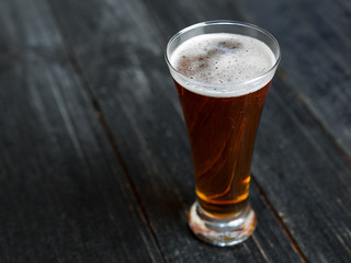 A glass of beer on a dark wooden table