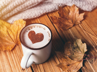 A mug of hot cappuccino coffee with a heart of cinnamon. Autumn seasonal background