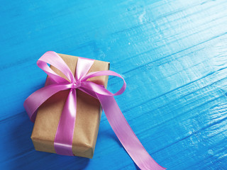 Gift Packed in Kraft paper and purple ribbon on blue background