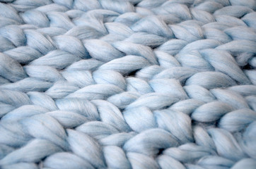 Merino wool handmade knitted large blanket, super chunky yarn, trendy concept. Close-up of knitted blanket, merino wool background