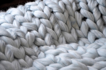 Merino wool handmade knitted large blanket, super chunky yarn, trendy concept. Close-up of knitted blanket, merino wool background
