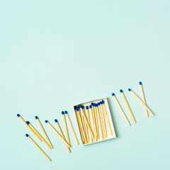 Bright wooden matches scattered from matchbox on a turquoise pastel color background
