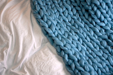 Cozy composition, closeup merino wool plaid in bed, warm and comfortable atmosphere. Knit background