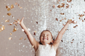 cute little child girl in princess dress on confetti background with silver bokeh. birtday party