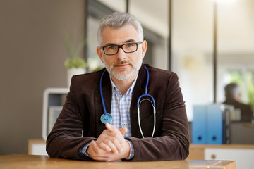 General practitioner sitting at his desk in medical office