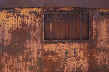 Rusty wall with a closed window. Old rough metal surface with scratches and stains. Perfect for background and grunge design.