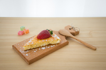 The cheesecake with strawberry on the wooden plate