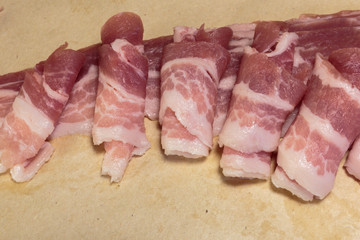 Raw rolls of bacon, close-up, ready for cooking.