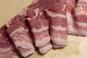 Raw rolls of bacon, close-up, ready for cooking.