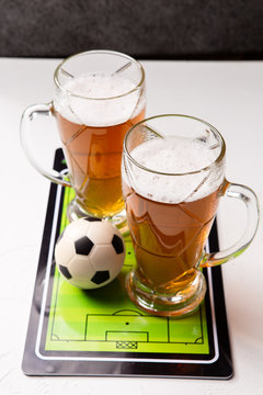 Photo on top of two mugs of frothy beer, table football, ball