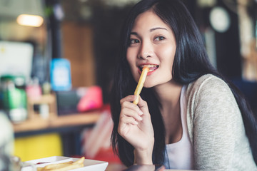 Beautiful young pretty Asian woman eating snack at coffee shop or cafe in the morning. Image in...