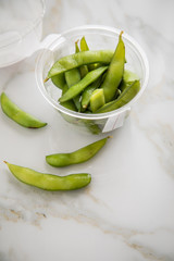 Frau isst portion grüne, japanische Edamame Sojabohnen in Plastik Lieferdienst Take Away Schale