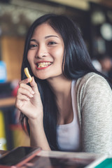 Beautiful young pretty Asian woman eating snack at coffee shop or cafe in the morning. Image in vintage warm tone.