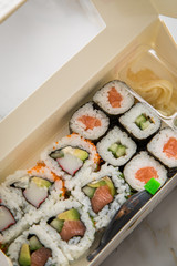 Maki und Inside Out California Sushi vom Lieferdienst mit Lachs, Surimi, Avocado, Gurken mit Ingwer, Wasabi und Soja Soße in Einweg Bento Box Verpackung