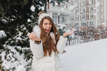 Excited brightful image of joyful amazing pretty winter girl having fun with snow outdoor on street. Happy moments, play with snowflakes, enjoying, positive emotions