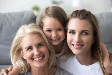 Head shot portrait of smiling grandmother, mother and daughter