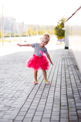 Little girl leaps for joy as she plays in the Autumn leaves in Arkansas. She has on a black polka dot top and hot pink skirt.