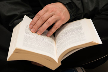 Man hands holding a book with dog-ears.